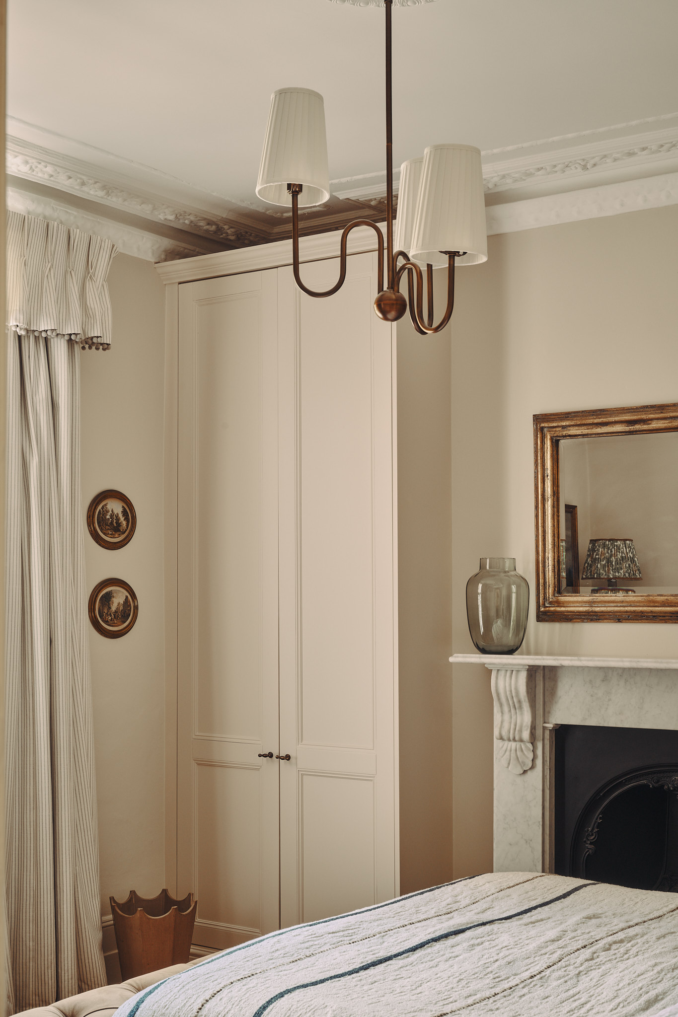 A bedroom with statement pendant and period fireplace